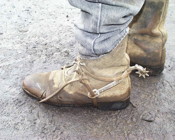 Closeup of landowner's boots and spurs during roadside land negotiation