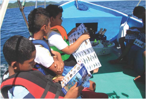 Children in lifejackets on boat studying fish identification guide