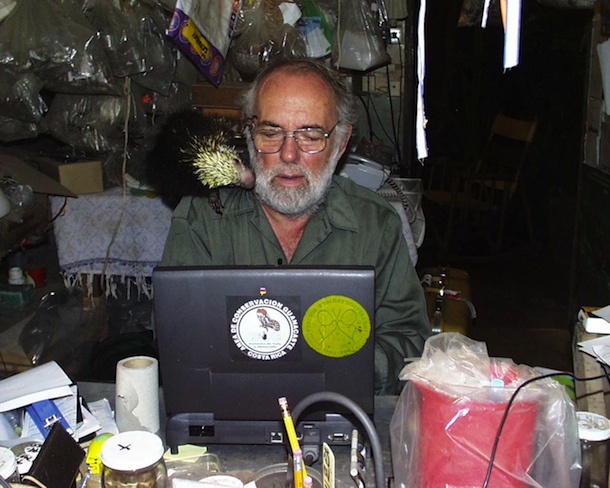 Dan Janzen at work with pet porcupine Espinita exploring his cheek, and 1999 vintage laptop